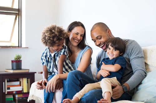Happy family sitting on sofa laughing together.